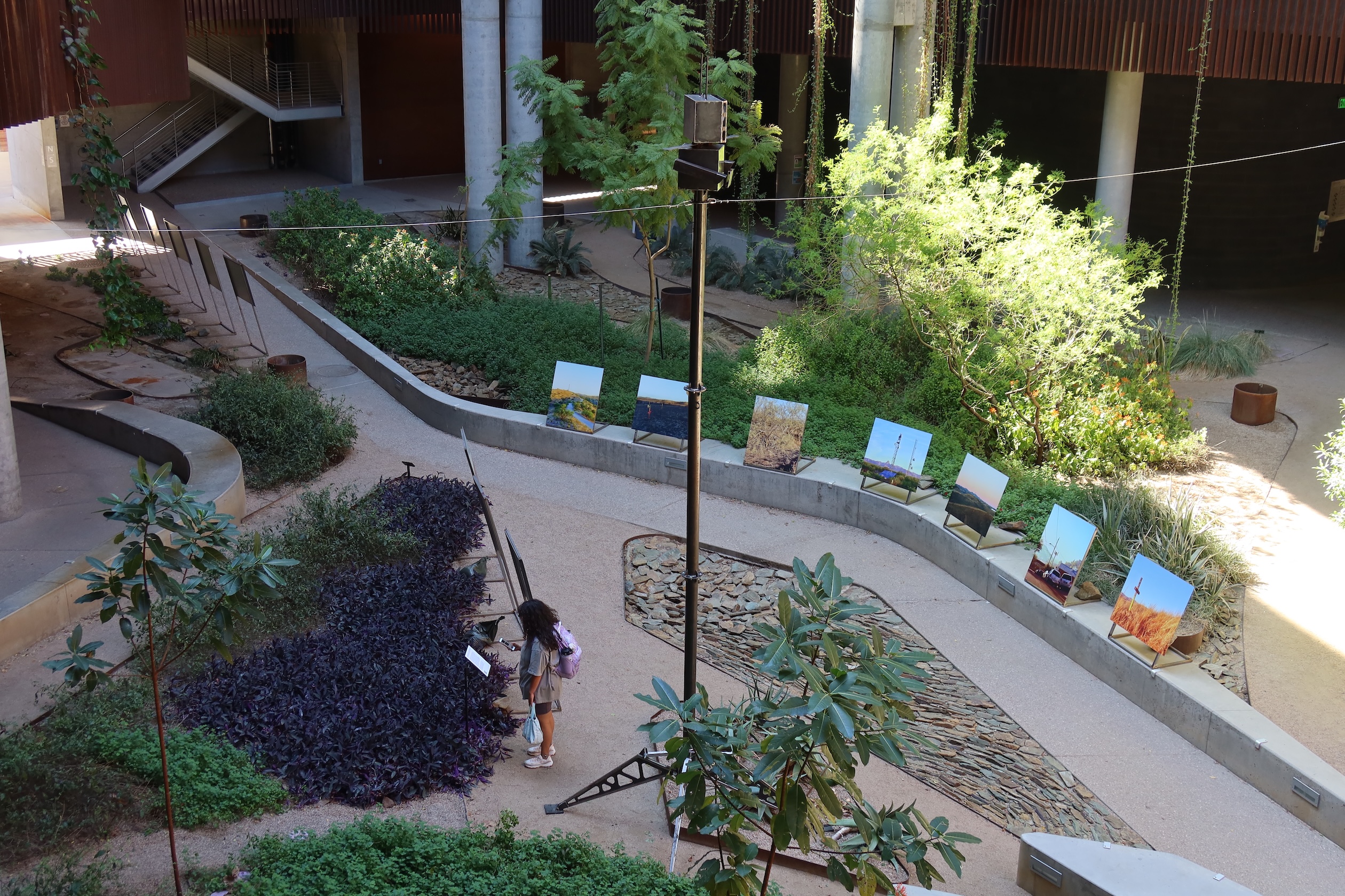 EFF An overhead view of a University of Arizona courtyard with a model surveillance tower and mounted photographs of surveillance technology. A person looks at one of the displays.